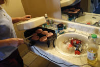 In this Oct. 11, 2018, photo, Dawn Robinson cooks food on a portable skillet in a room at the Fireside Inn motel in Reno, Nev. Robinson and her partner Dave Frazier get much of their food from local food pantries. (AP Photo/John Locher)