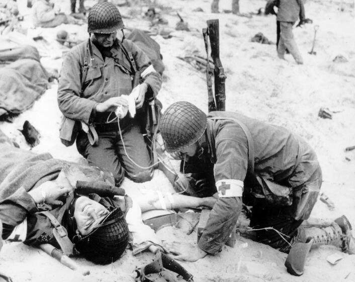 Medics treat a wounded U.S. soldier on D-Day during the Normandy landings in Nazi-occupied France.