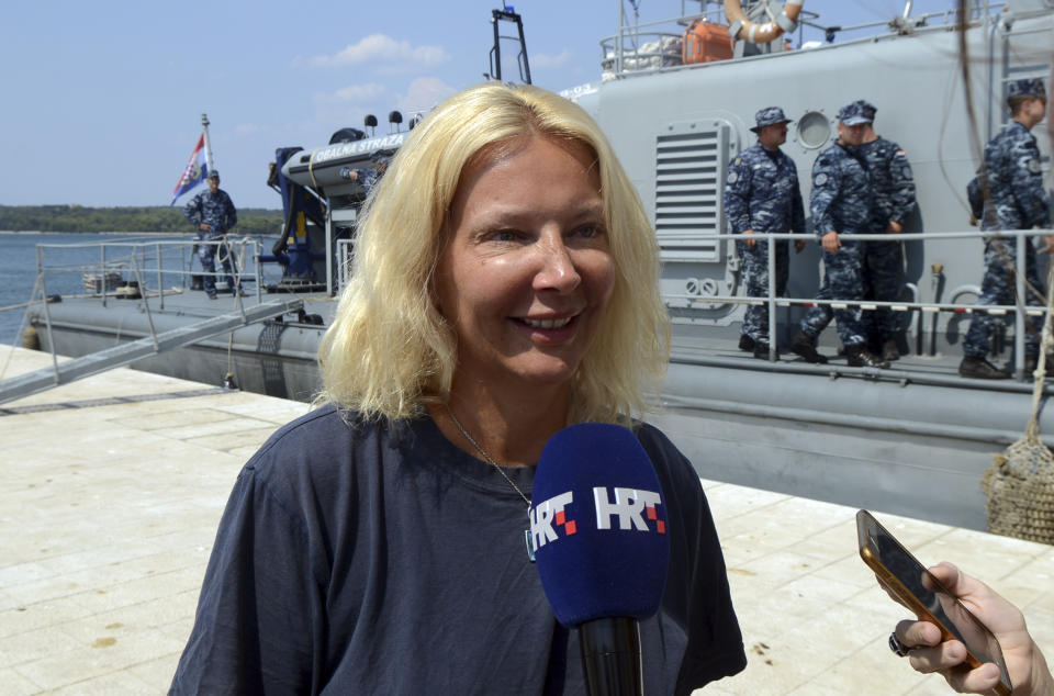 In this photo taken Aug. 19, 2018, a woman who identified herself as Kay from England, is interviewed by local media in front of a Croatian Coast Guard vessel in the port in Pula, Croatia. A British woman was rescued Sunday after falling from a cruise ship and spending 10 hours in the Adriatic Sea at night, Croatia's coast guard said. (AP Photo)