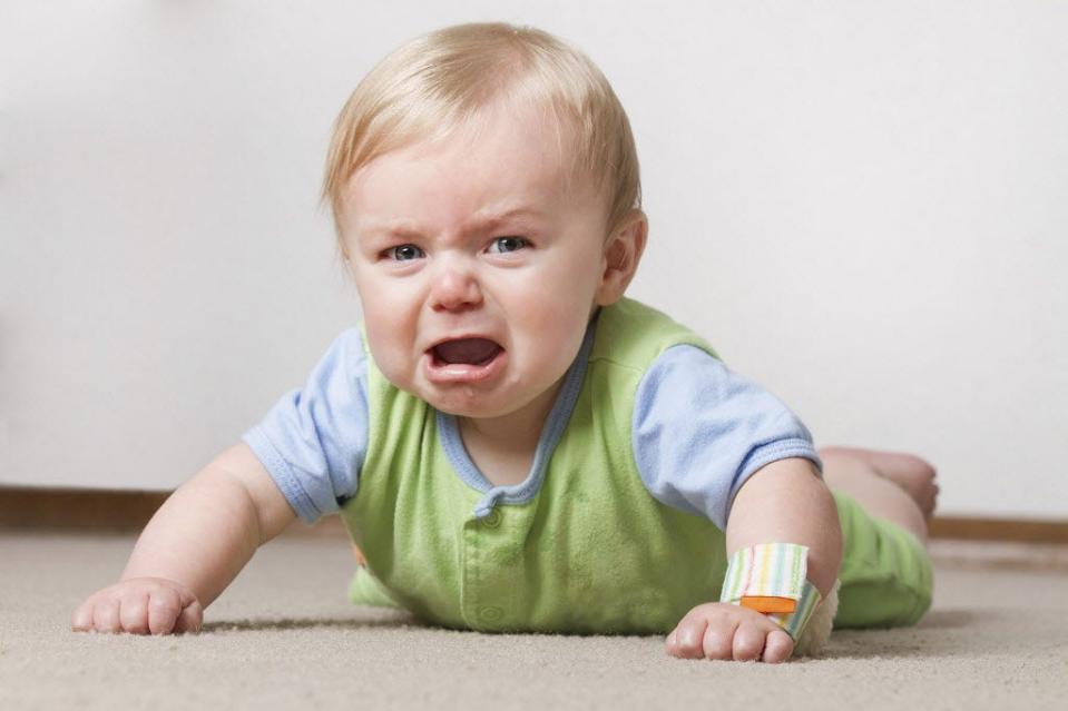 A toddler on the floor crying.