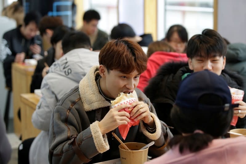 A customer eats a baked bun with chicken at a pork bun chain restaurant Xishaoye in Beijing
