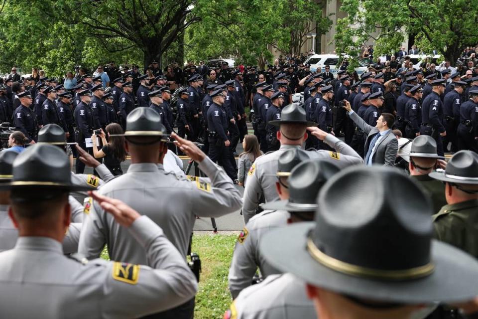 Law officers salute as a horse-drawn carriage carries the body of officer Joshua Eyer to First Baptist Church on Friday, May3, 2024. Officer Eyer was killed while serving a warrant in east Charlotte on Monday, April 29, 2024