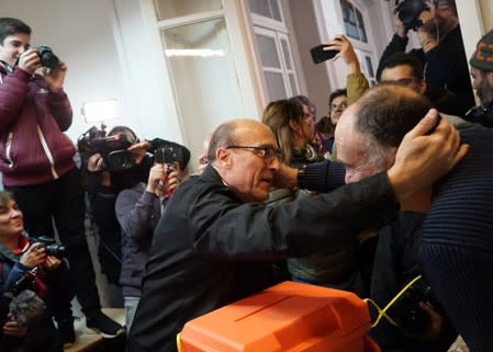Former mayor of Montevideo Daniel Martinez of the Frente Amplio hugs an electoral official after casting his vote during primary elections ahead of the presidential elections later this year, in Montevideo