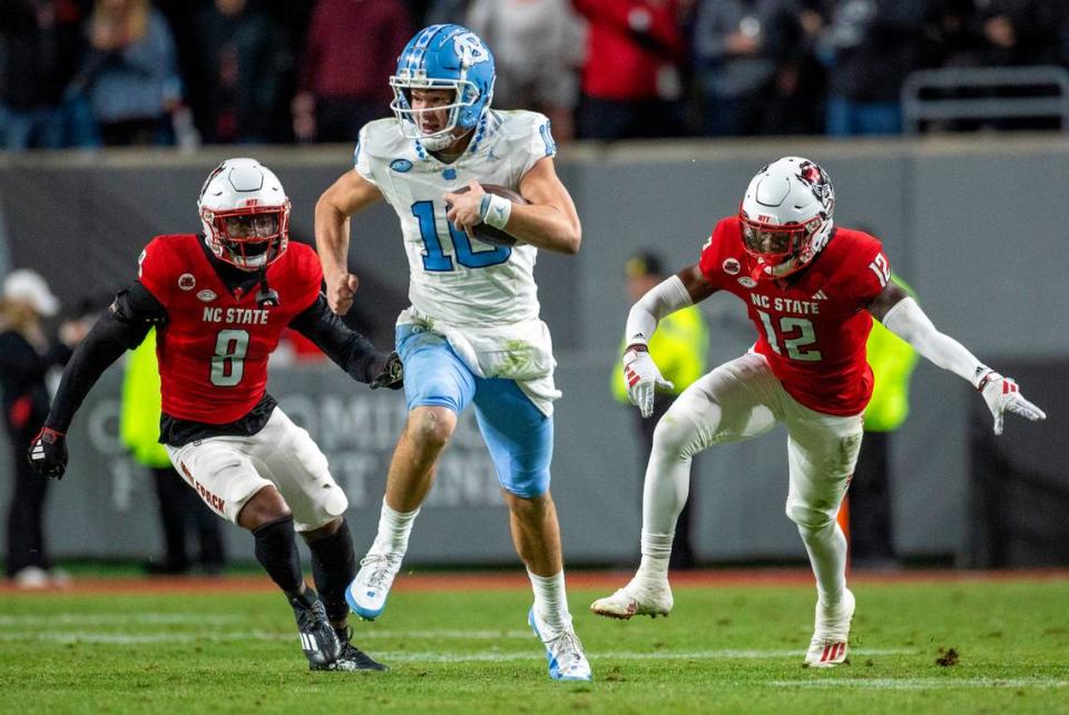 North Carolina quarterback Drake Maye (10) breaks open on a 56-yard gain ahead of N.C. State’s Robert Kennedy (8) and Devan Boykin (12) in the third quarter against N.C. State on Saturday, November 25, 2023 at Carter-Finley Stadium in Raleigh, N.C. Robert Willett/rwillett@newsobserver.com