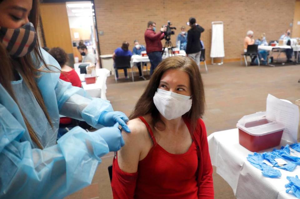 Natalie Macpherson, an English teacher at Sanderson High School, smiles after Crystal Truitt gave her a COVID-19 vaccine shot during a mass vaccine event at Wake County Commons Building in Raleigh, N.C., Wednesday, February 24, 2021. Wednesday was the first day preK-12 public, private and charter schools, as well as childcare workers, became eligible to begin getting shots.