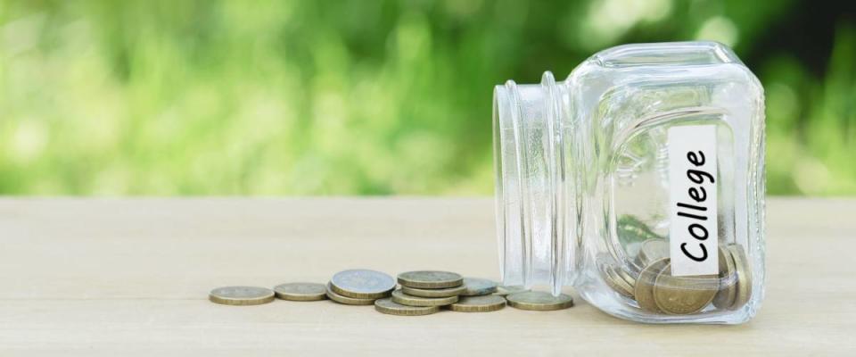 College savings concept \ Money(coins) near an empty jar on a table, outdoors, green background, toned picture