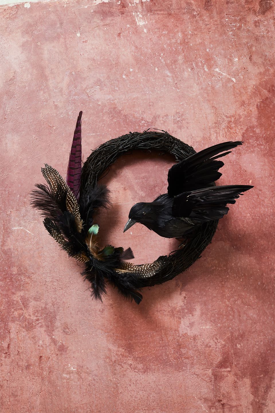 <p>Take a simple feather wreath to the dark side by attaching a black artificial bird and sprinkling with glitter.</p><p><strong>RELATED: </strong><a href="https://www.goodhousekeeping.com/holidays/halloween-ideas/g79/diy-halloween-wreaths/" rel="nofollow noopener" target="_blank" data-ylk="slk:30+ Scary-Good Halloween Wreaths to Hang;elm:context_link;itc:0;sec:content-canvas" class="link ">30+ Scary-Good Halloween Wreaths to Hang</a></p>