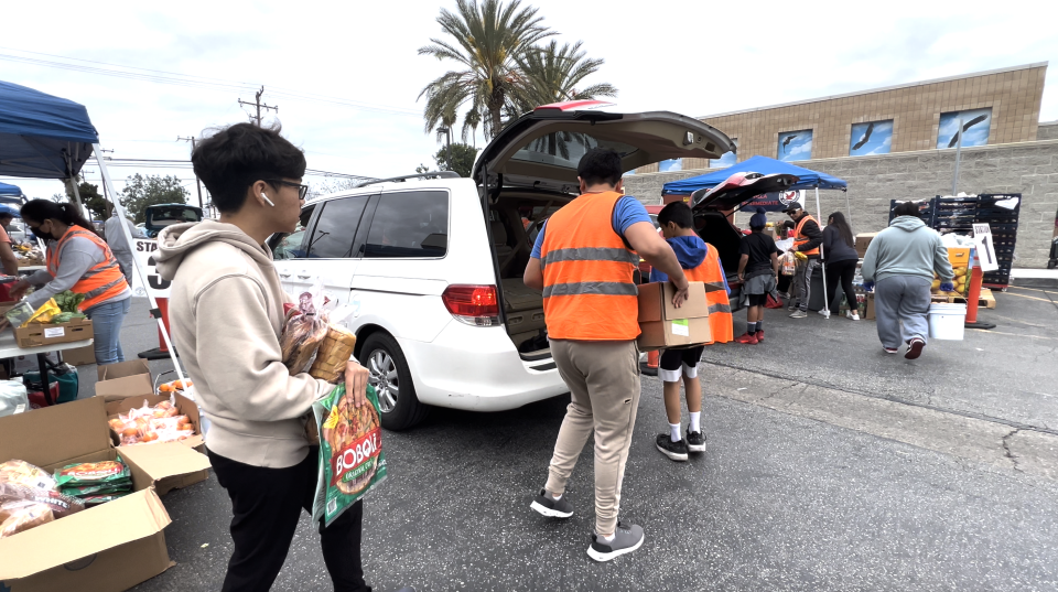Volunteers place grocery items in the car trunks of recipients / Credit: Simrin Singh/CBS News