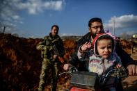 <p>A Turkish-backed Syrian rebel fighter stands guard at a checkpoint as a family passes on motobike in the Syrian town of Azaz on a road leading to Afrin, on Feb. 1, 2018. (Photo: Ozan Kose/AFP/Getty Images) </p>