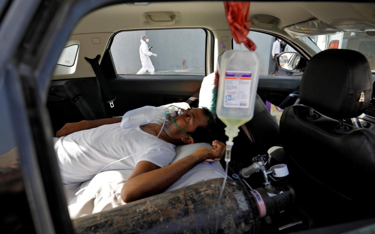 A patient with breathing problems is seen inside a car while waiting to enter a COVID-19 hospital  - REUTERS/Amit Dave