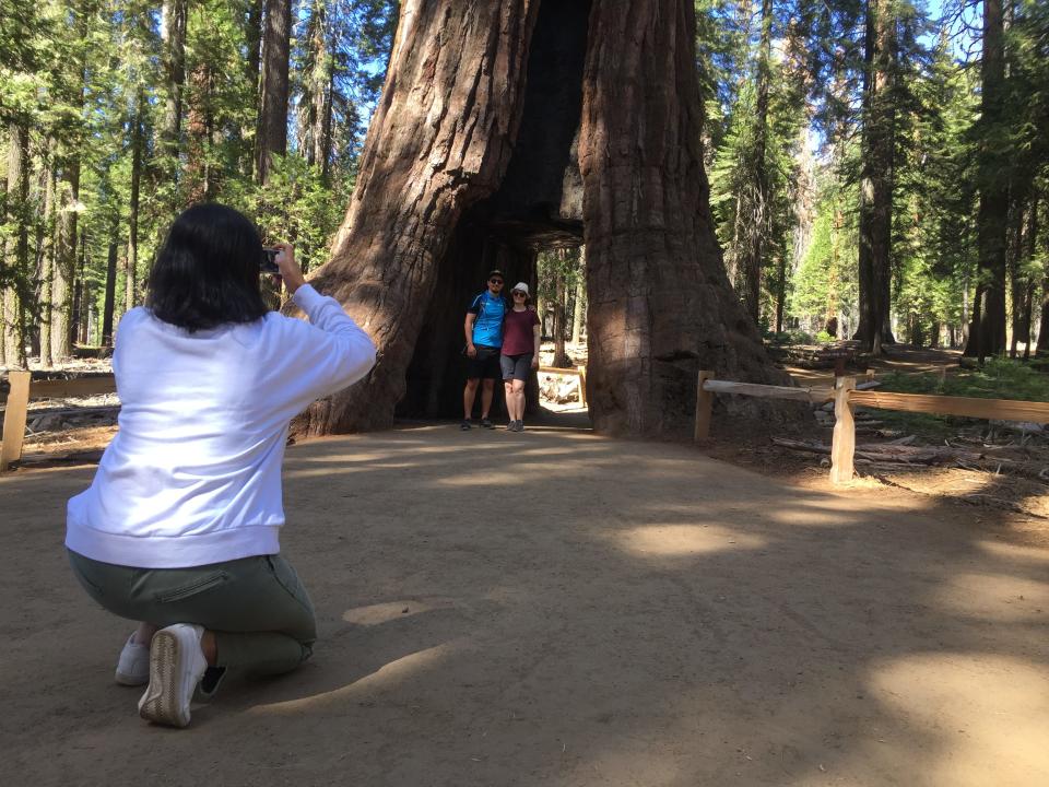 Tourists pose for a photo with a tunnel tree in the Mariposa Grove of Giant Sequoias in Yosemite National Park in 2018.