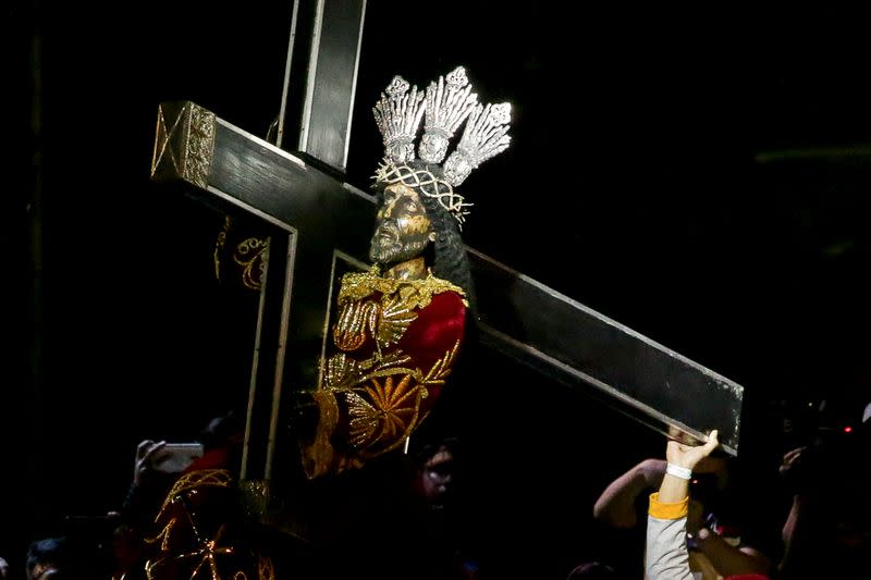 A devotee holds on to the religious statue of the Black Nazarene during the annual Catholic procession that celebrates its feast day in Manila