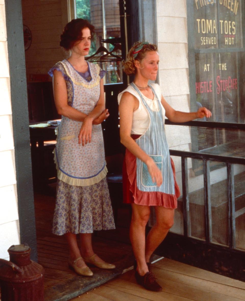 Mary Stuart Masterson and Mary-Louise Parker stand on a porch in aprons in a scene from "Fried Green Tomatoes."