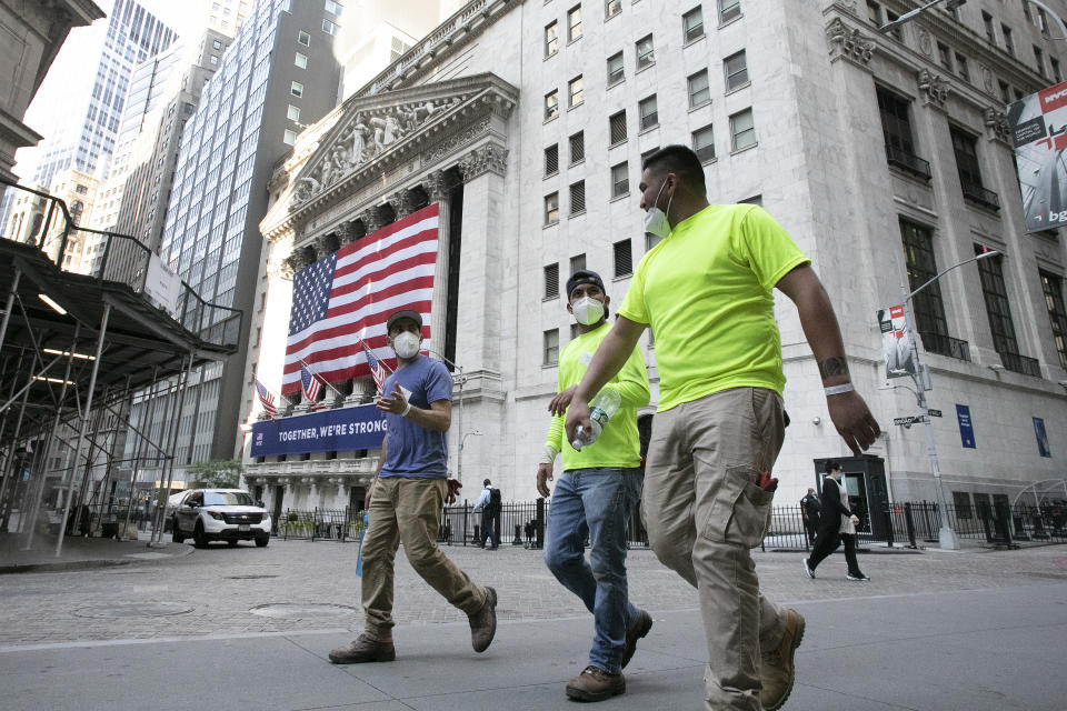 Workers wearing masks walk by the New York Stock Exchange during the coronavirus pandemic, Thursday, July 9, 2020, in New York. (AP Photo/Mark Lennihan)
