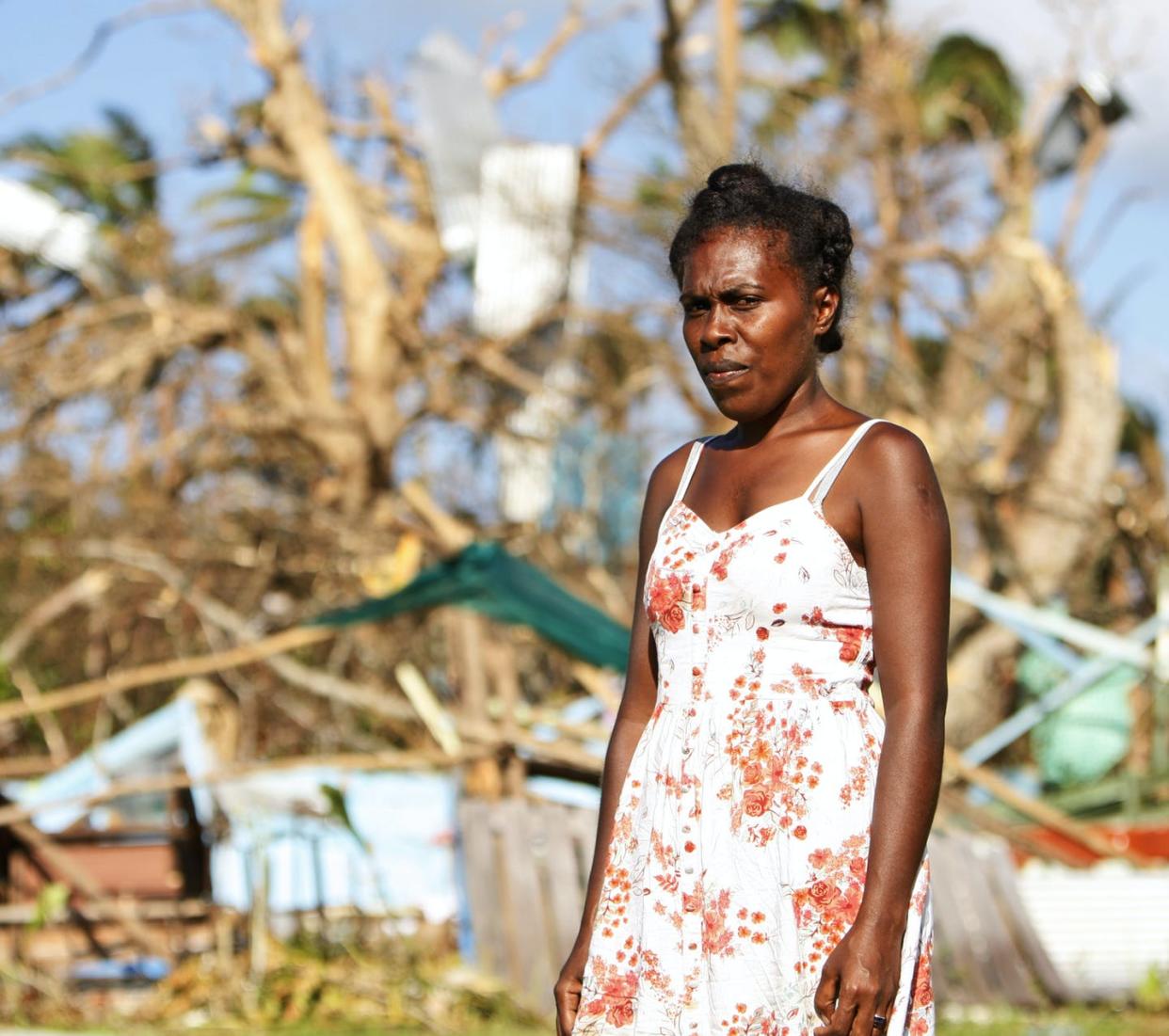 <span class="caption">Melizabeth Uhi, a school principal, stands in front of her destroyed home in Vanuatu, a week after Cyclone Pam tore through the South Pacific archipelago in 2015.</span> <span class="attribution"><span class="source">Nick Perry/AP</span></span>