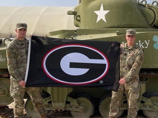 U.S. Army Pfc. Trevor Mattox, left, and fellow soldier Brian Hopson of Indianapolis, Ind., show the flag he was able to fly in Kuwait after UGA won the national championship.