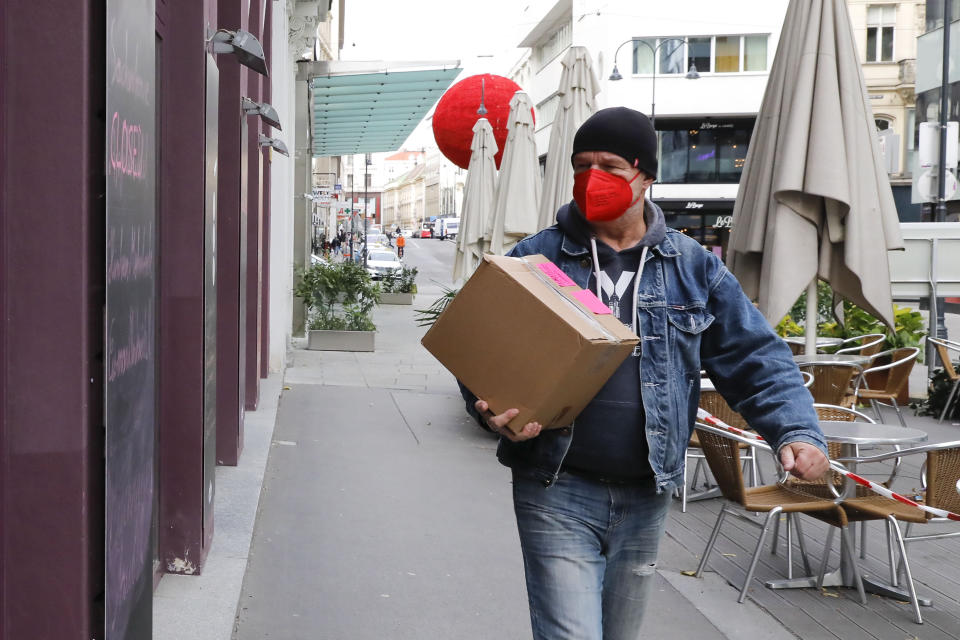 A person wearing a mask, walks on the street in the city center in Vienna, Austria, Tuesday, Nov. 30, 2021. (AP Photo/Lisa Leutner)