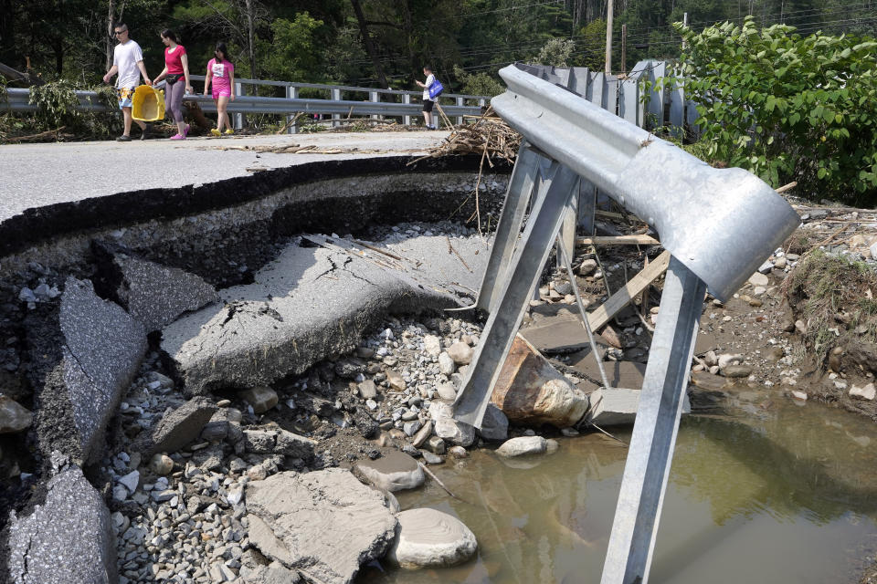 Varias personas caminan por un puente dañado por inundaciones, el martes 11 de julio de 2023, en Ludlow, Vermont. (AP Foto/Steven Senne)