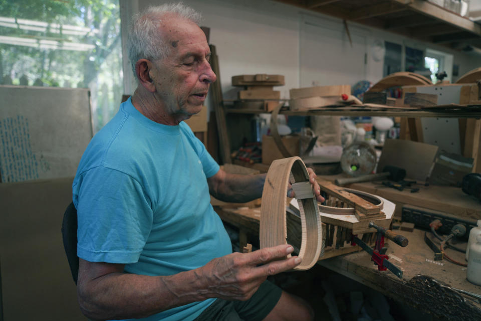 Mike Dulak holds the frame of a mandolin, in his workshop in Rocheport, Mo. on Friday, Sept. 8, 2023. Over the past 30 years, Dulak has made thousands of mandolins, and says he finds a sense of spirituality in working with the wood, just as he does playing his guitar. But Dulak, along with the largest group of Americans, does not associate himself with any religion. (AP Photo/Jessie Wardarski)