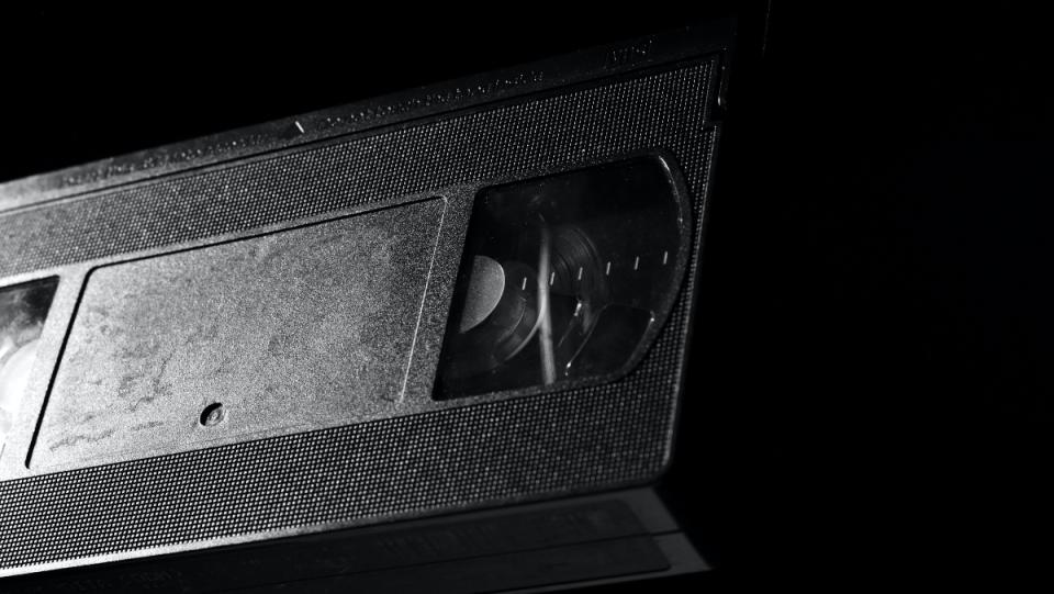 a photo of a plain black VHS tape from video store on a black background 