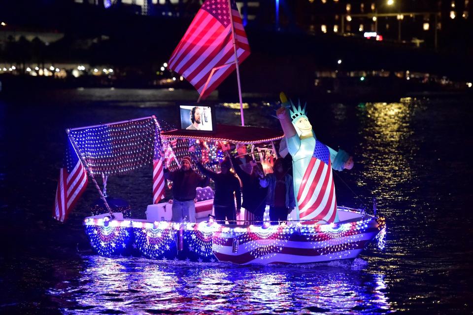 Decked out in red, white and blue lights, a boat makes its way past Riverfront Plaza as part of the annual Light Boat Parade.