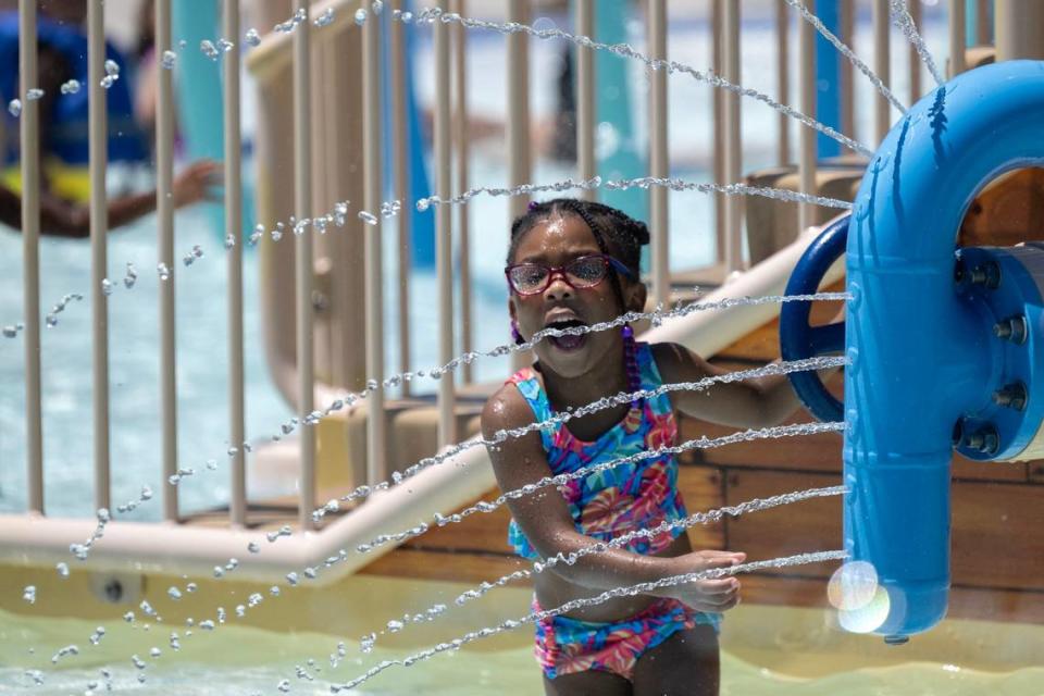 Zalaeyah Kirk, 3, of Citrus Heights plays with apparatus at North Natomas Aquatic Complex as temperatures reach 103 degrees on Monday, July 1, 2024, in Sacramento. Her father, Xzavion Kirk, says she cries when they have to leave the pool and begs to stay.