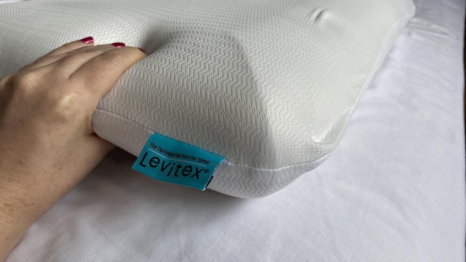 A hand squeezing the foam of the Levitex Sleep Posture Pillow