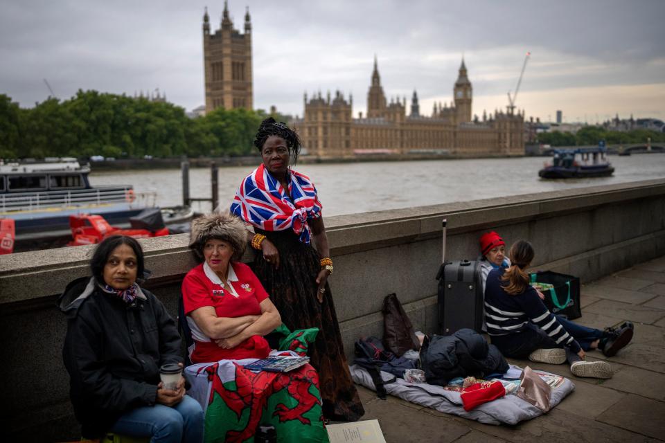 Vanessa, Anne and Grace, from left to right, wait opposite the Palace of Westminster to be first in line bidding farewell to Queen Elizabeth II (AP)