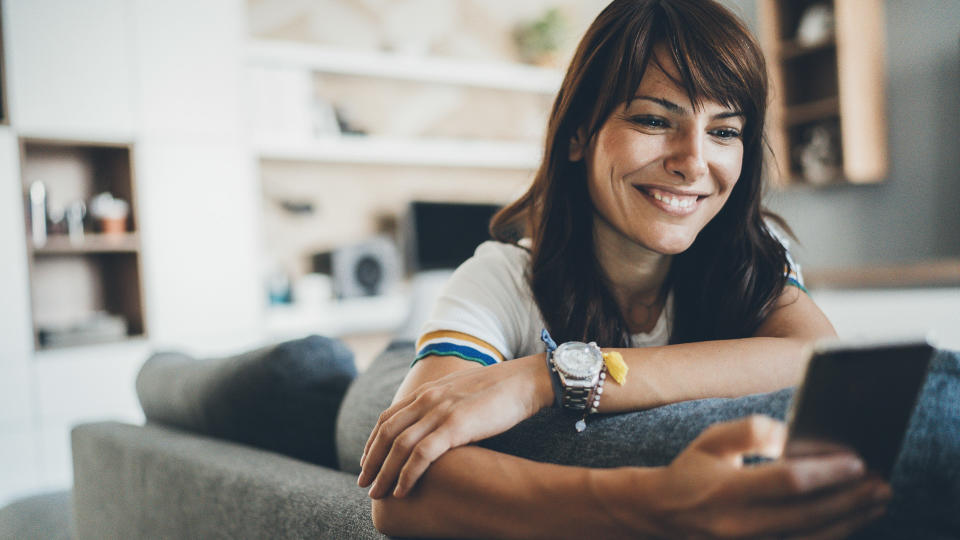 Young bautiful woman texting surfing the net on the sofa at home.