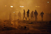 Engulfed by tear gas thrown by police, protesters walk for cover during clashes with police, near the parliament in Athens.