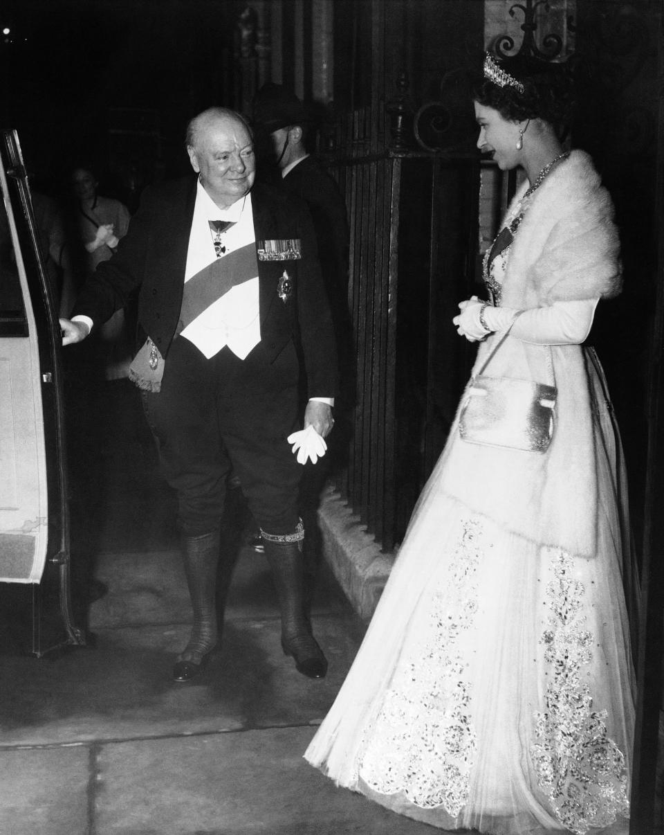 ARCHIVO – El primer ministro británico Sir Winston Churchill, vestido de gala, abre la puerta de un auto para la reina Isabel II tras una cena de despedida para el primer ministro en la residencia oficial de Downing Street, en Londres el 5 de abril de 1955. En sus siete décadas en el trono, la reina Isabel II vio 15 primeros ministros británicos ir y venir de Winston Churchill a Margaret Thatcher, Boris Johnson y la más reciente, Liz Truss. (Foto AP, archivo)