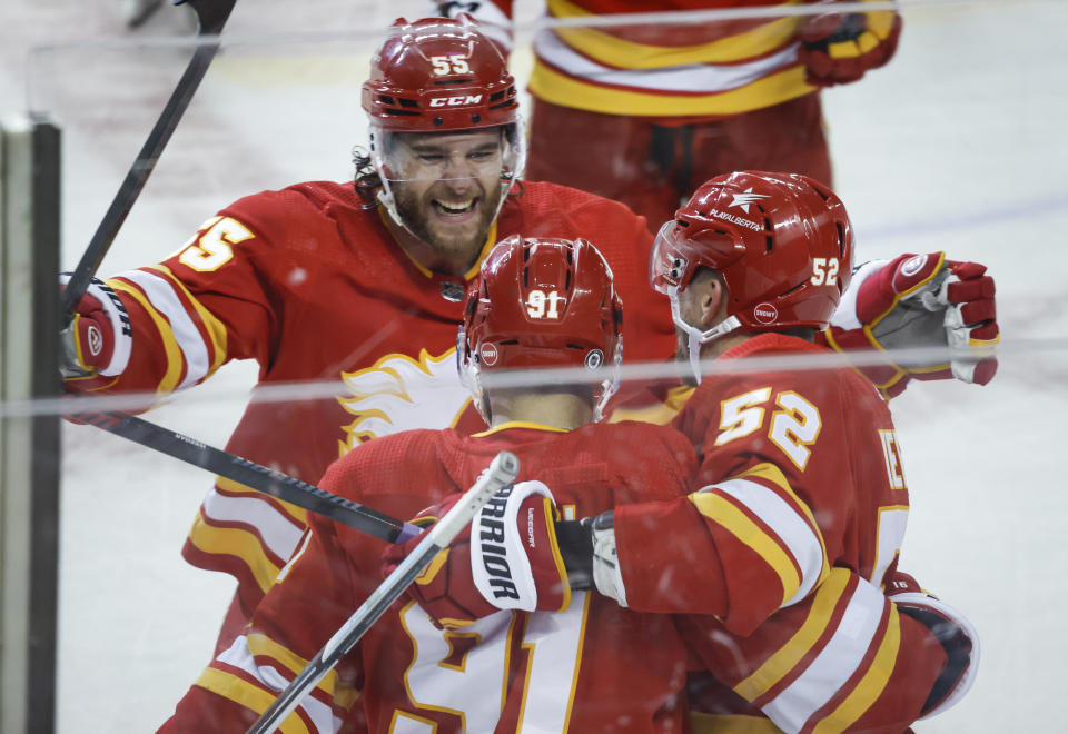 Calgary Flames forward Nazem Kadri (91) celebrates his overtime goal against the Dallas Stars with Noah Hanifin (55) and MacKenzie Weegar (52) during an NHL hockey game in Calgary, Alberta, Thursday, Nov. 30, 2023. (Jeff McIntosh/The Canadian Press via AP)