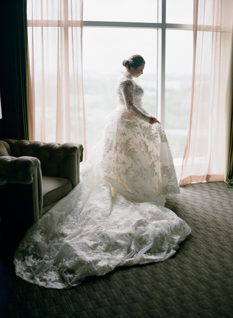 bride in flowing floral dress by window