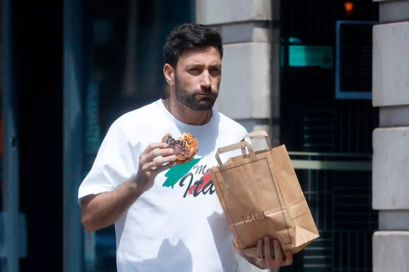 Giovanni dressed in a causal outfit of a white T-shirt, black jogging bottoms and trainers