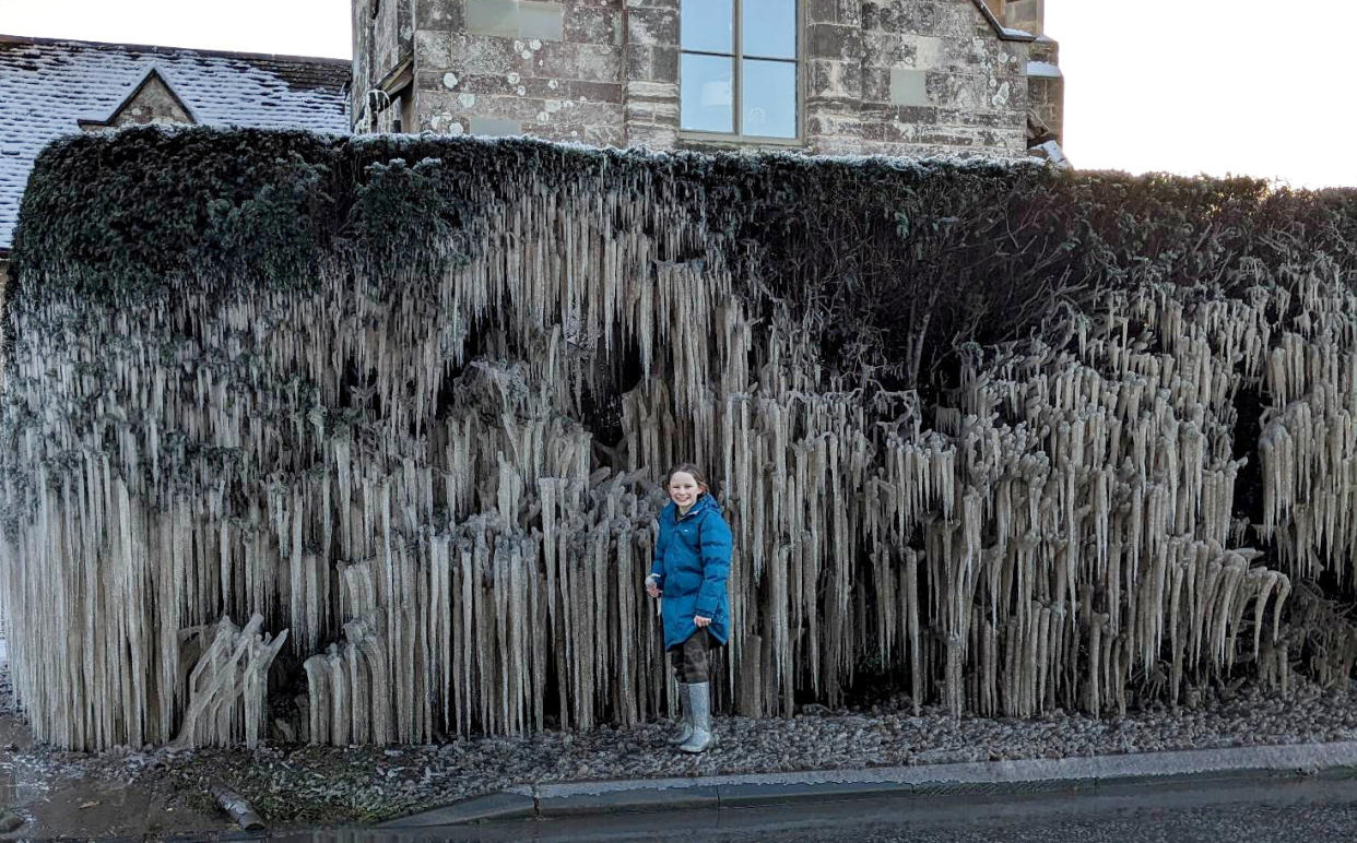 Sabrina Staunton, 9, stands next to the icicles in Gloucestershire. (SWNS)