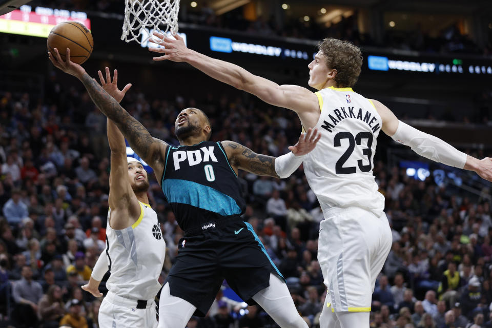 Portland Trail Blazers guard Damian Lillard (0) drives to the basket against Utah Jazz guard Johnny Juzang, left, and Utah Jazz forward Lauri Markkanen (23) during an NBA basketball game, Wednesday, March 22, 2023, in Salt Lake City. (AP Photo/Jeff Swinger)