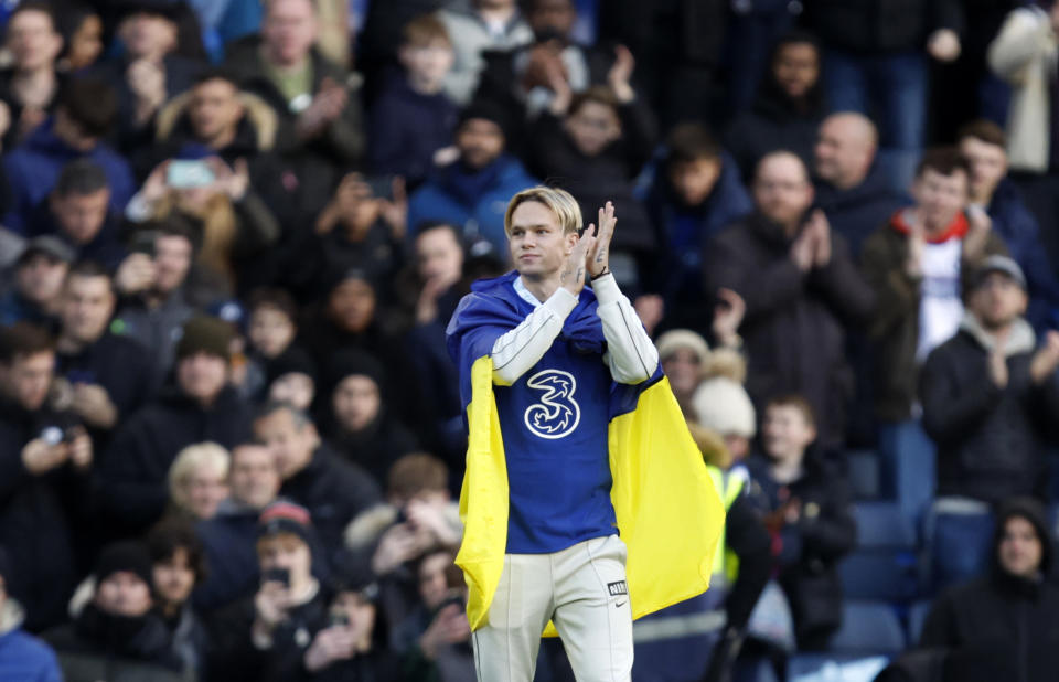 Chelsea's Mykhailo Mudryk, holds Ukreainian flag and applauds during a half time of the English Premier League soccer match between Chelsea and Crystal Palace at Stamford Bridge Stadium in London, Sunday, Jan. 15, 2023. (AP Photo/David Cliff)