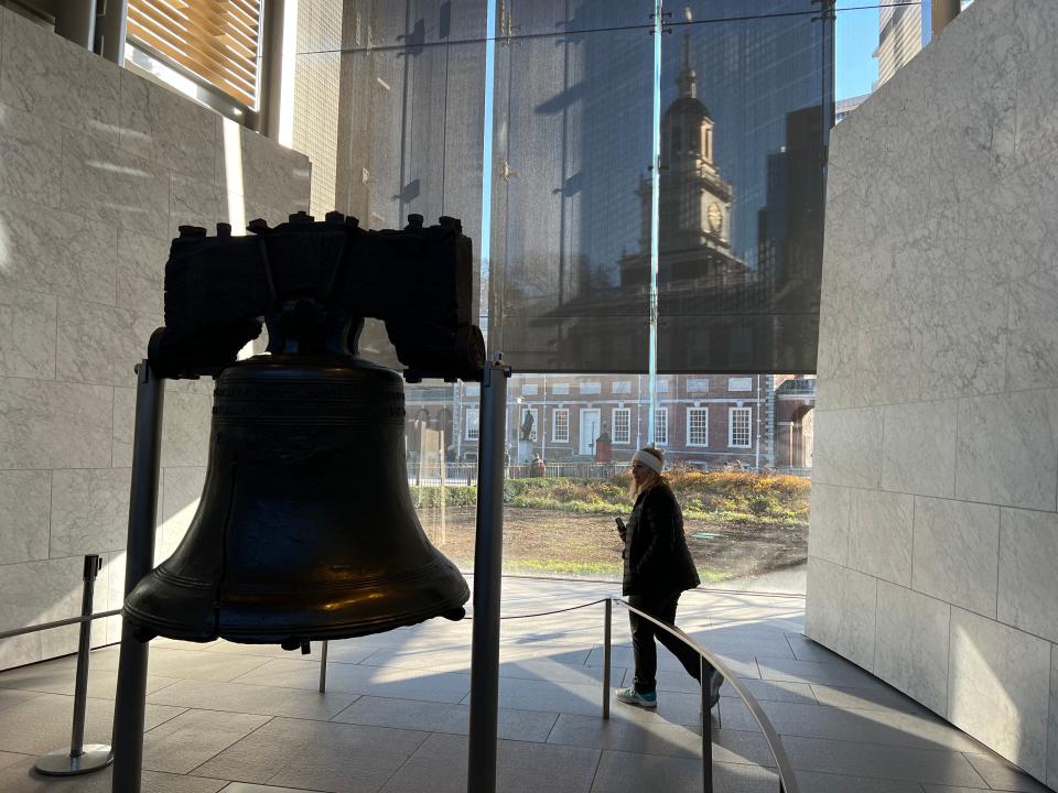 Toni Woods looks at the Liberty Bell, with Independence Hall in the background.