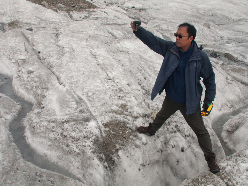 This Sept. 22, 2018 photo shows glaciologist Wang Shijin photographing an ice crevasse in the Baishui Glacier No. 1 on the Jade Dragon Snow Mountain in the southern province of Yunnan in China. Scientists say the glacier is one of the fastest melting glaciers in the world due to climate change and its relative proximity to the Equator. It has lost 60 percent of its mass and shrunk 250 meters since 1982. (AP Photo/Sam McNeil)