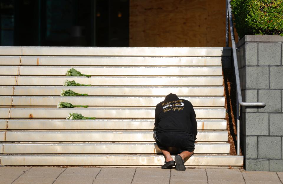 A man kneels in front of the steps of Old National Bank Tuesday morning after Monday's mass shooting there Monday morning, killing five people and injured nine, including two Louisville Metro Police officers in downtown Louisville, Ky.  April 11, 2023