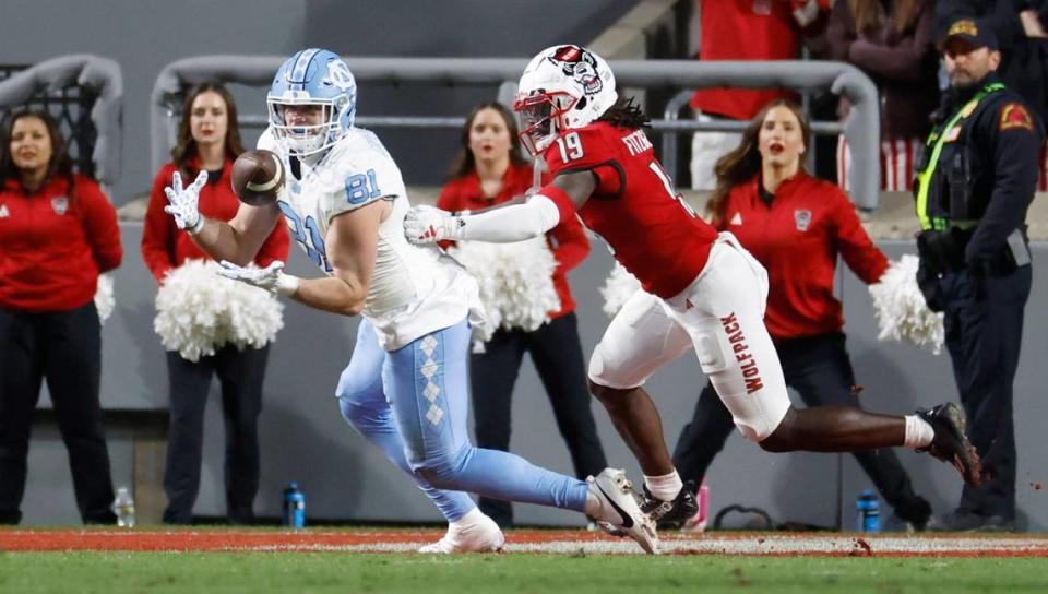North Carolina tight end John Copenhaver (81) pulls in a 15-yard touchdown reception as N.C. State safety Bishop Fitzgerald (19) defends during the first half of N.C. State’s game against UNC at Carter-Finley Stadium in Raleigh, N.C., Saturday, Nov. 25, 2023.