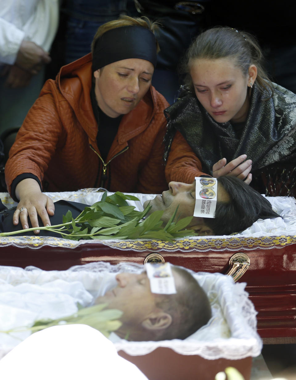 Relatives mourn in front of the coffins of four people killed in last week's operation, during a commemorative service in the center of Slovyansk, eastern Ukraine, Wednesday, May 7, 2014. The U.S. and European nations have increased diplomatic efforts ahead of Ukraine's May 25 presidential election, as a pro-Russian insurgency continues to rock the country's eastern regions. (AP Photo/Darko Vojinovic)