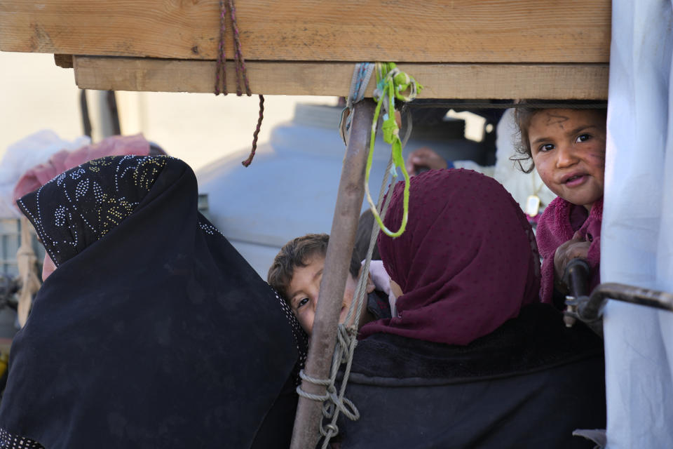 Syrian refugee child sit on the top of a truck with their mothers, as they wait at a gathering point to cross the border back home to Syria, in the eastern Lebanese border town of Arsal, Lebanon, Wednesday, Oct. 26, 2022. Several hundred Syrian refugees boarded a convoy of trucks laden with mattresses, water and fuel tanks, bicycles – and, in one case, a goat – Wednesday morning in the remote Lebanese mountain town of Arsal in preparation to return back across the nearby border.(AP Photo/Hussein Malla)