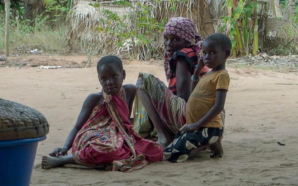 A woman with children watch as Rwandan soldiers patrol in the village of Mute, in Cabo Delgado province, Mozambique