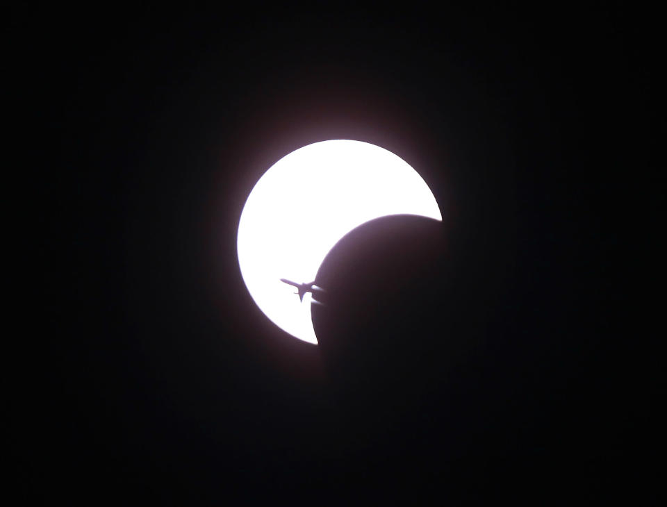 An aircraft flies past a solar eclipse in Bangkok January 15, 2010. The annular eclipse of the sun, which will last for over 11 minutes during its maximum duration, will be visible from a 300-km wide track that passes half of the earth, according to NASA. REUTERS/Chaiwat Subprasom