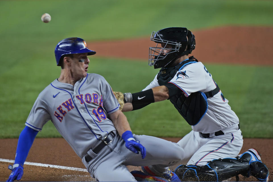 Miami Marlins catcher Jacob Stallings, right, is unable to hang on to the throw as New York Mets' Mark Canha (19) slides in safely into home plate on a single by Brandon Nimmo during the third inning of a baseball game, Sunday, July 31, 2022, in Miami. (AP Photo/Wilfredo Lee)