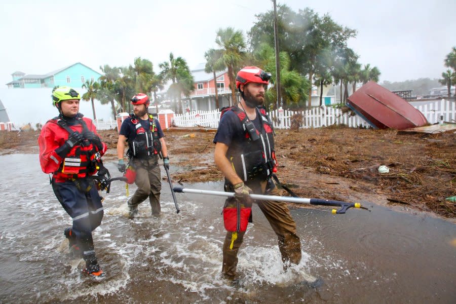 Rescue workers with Tidewater Disaster Response, from left, Zack Hoeth, Zack McCue, and Mike Foster, of Fairfax, Va., search SW 358 Highway for people in need of help Wednesday, Aug. 30, 2023, after the arrival of Hurricane Idalia. (Douglas R. Clifford/Tampa Bay Times via AP)