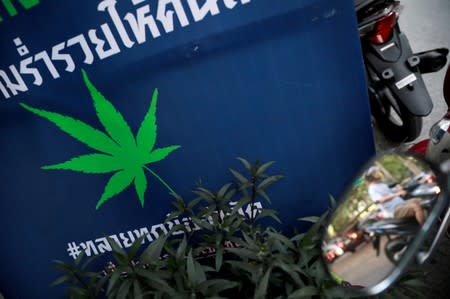 FILE PHOTO: A man drives his motorbike near an election campaign poster in Bangkok