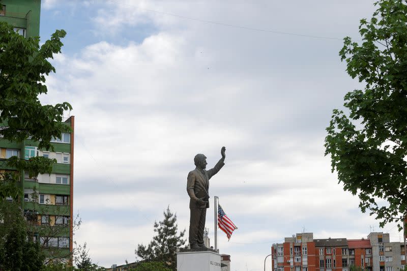 U.S. flag flies next to the statue of the former U.S. president Bill Clinton, in Pristina