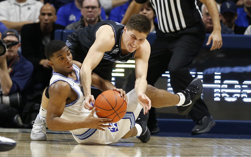 Xavier guard KyKy Tandy, left, and Villanova guard Collin Gillespie, right, fight for a loose ball during the second half of an NCAA college basketball game, Saturday, Feb. 22, 2020, in Cincinnati. (AP Photo/Gary Landers)